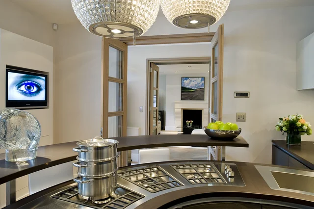 A kitchen hob and curved worktop sit beneath circular pendant lights, with open double doors beyond.